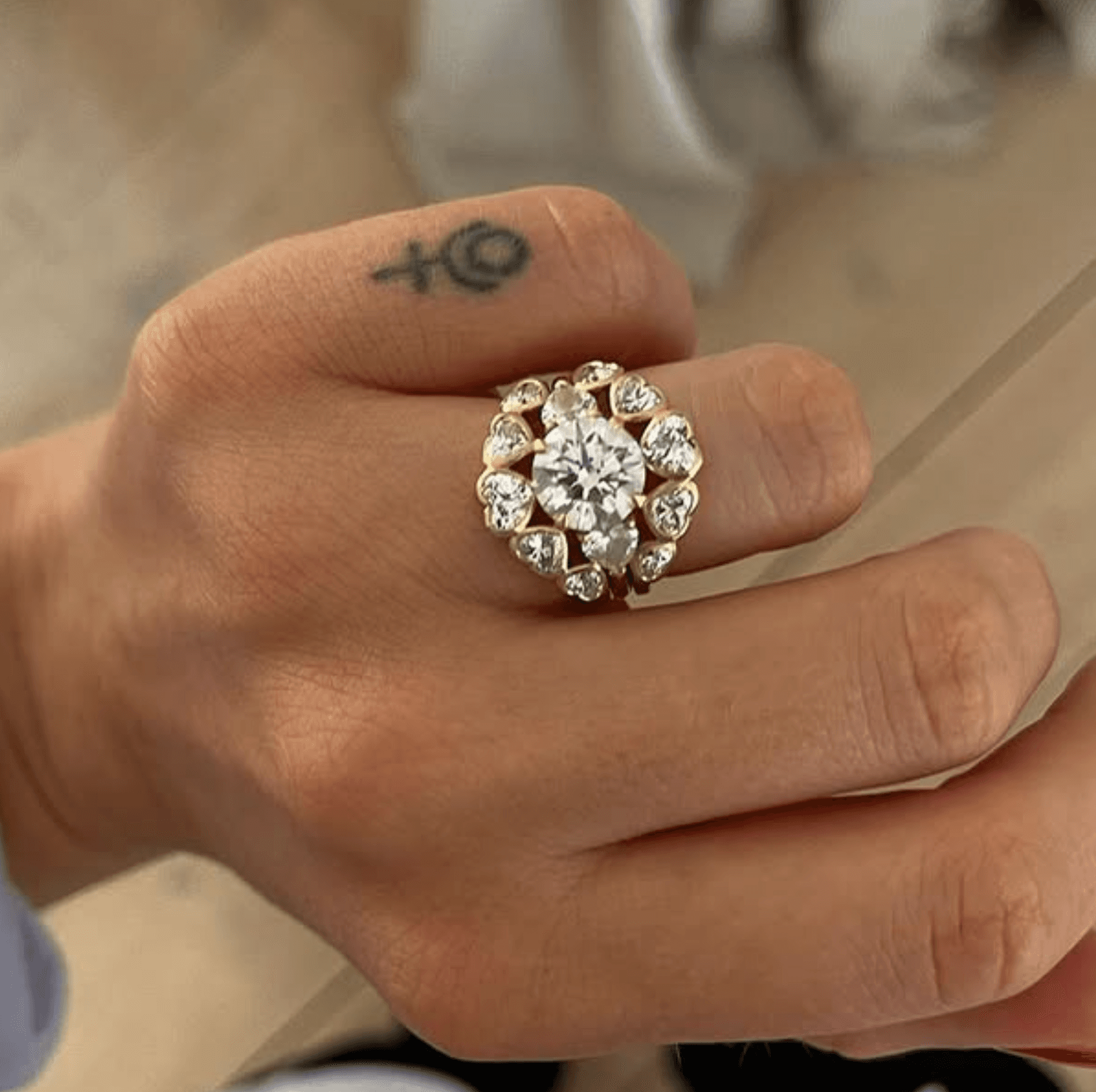 Statement diamond halo cluster ring worn on a hand - a large round brilliant centre stone surrounded by ten pear-cut diamonds in 18ct gold, photographed in the studio