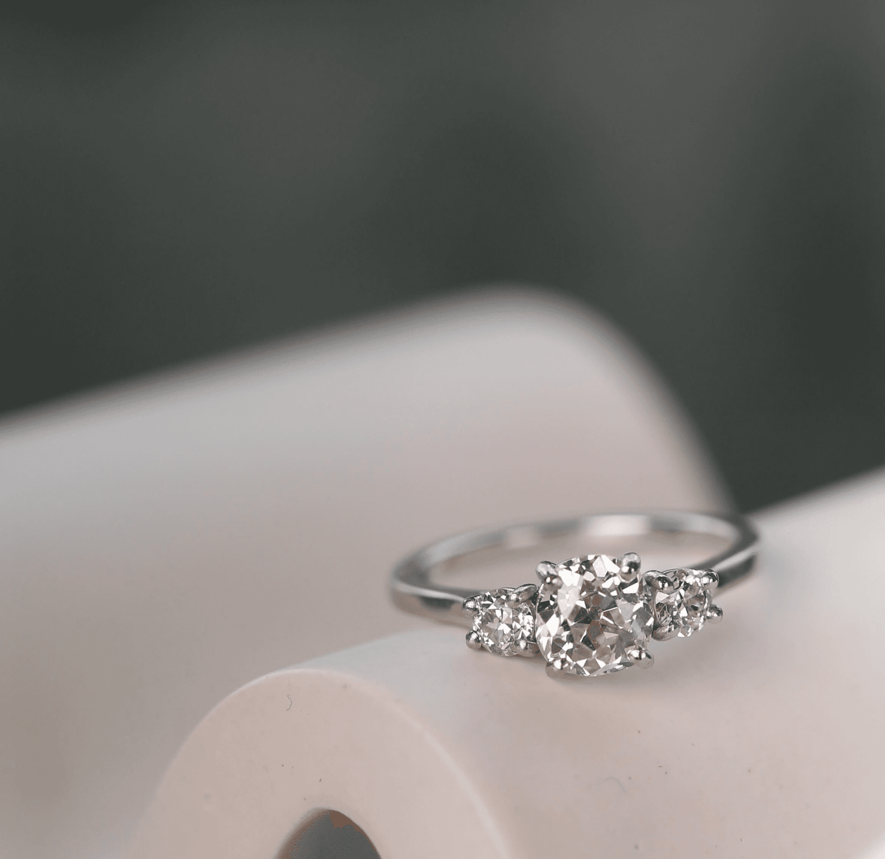 Three-stone old-cut diamond ring in platinum, soft teal background